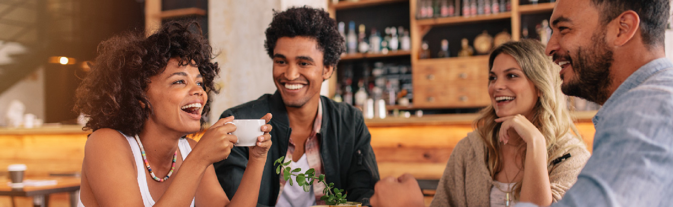 Group of young adult friends laughing in a trendy coffee shop.